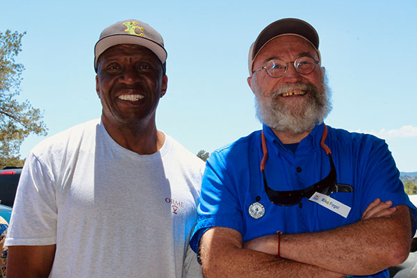 Two men standing and smiling posing for a picture at a party event