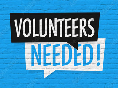 Volunteers Needed wording painted on blue brick background